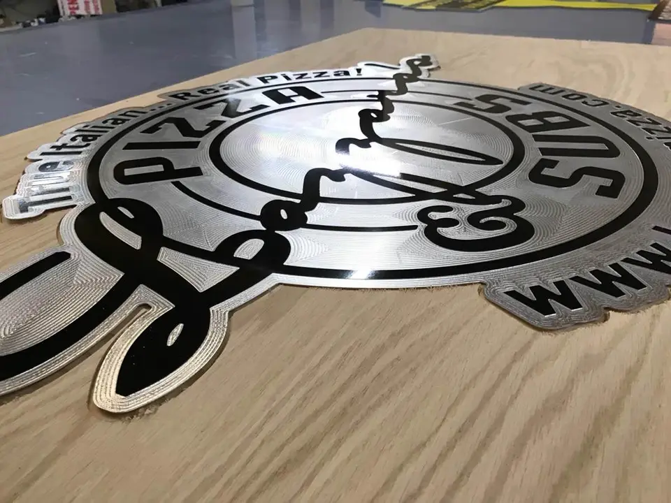 Shiny Lazzara’s Pizza sign with cut-out lettering on a worktable