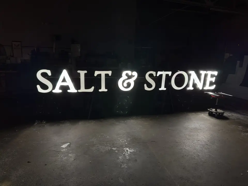 Illuminated white SALT & STONE letters inside the shop