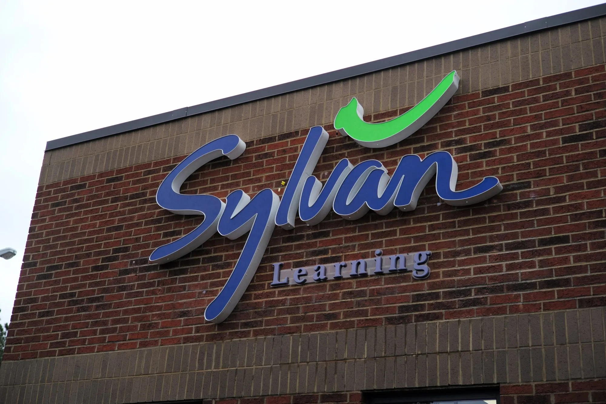 Blue and green Sylvan Learning letters on a brick storefront